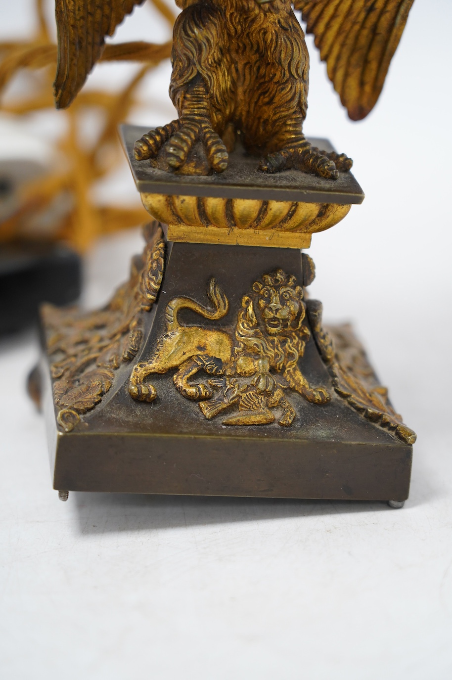 An ormolu table lamp in the form of an eagle with a laurel wreath around its neck, fitted with a grey shade, 39cm high overall. Condition poor to fair, three feet missing to lamp